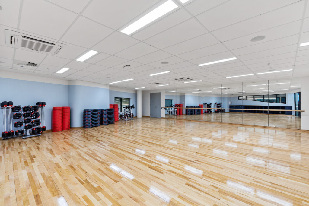 Group Fitness Room timber floors, mirrors and dance bare at the back and step equipment along the wall