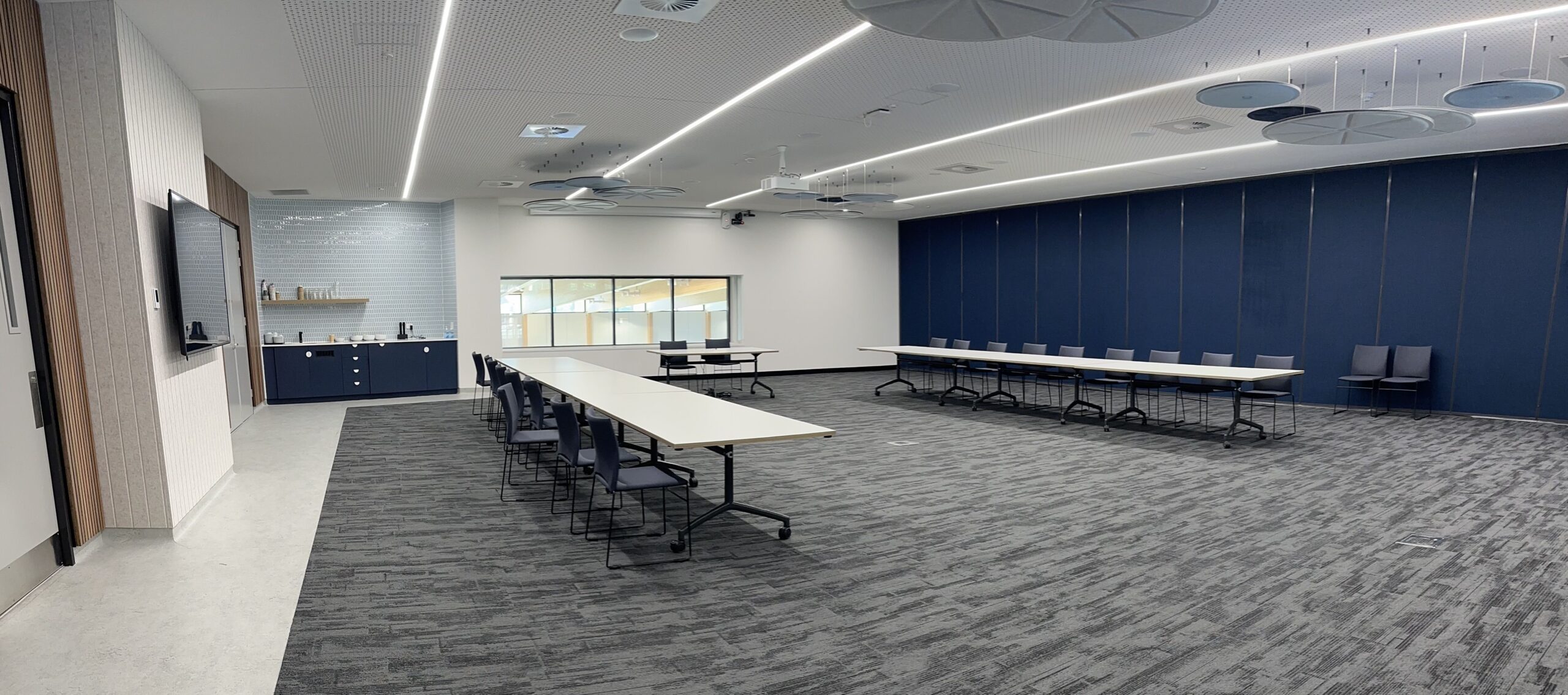 Function Room with window and coffee station at the back and two long stable with seating down both sides