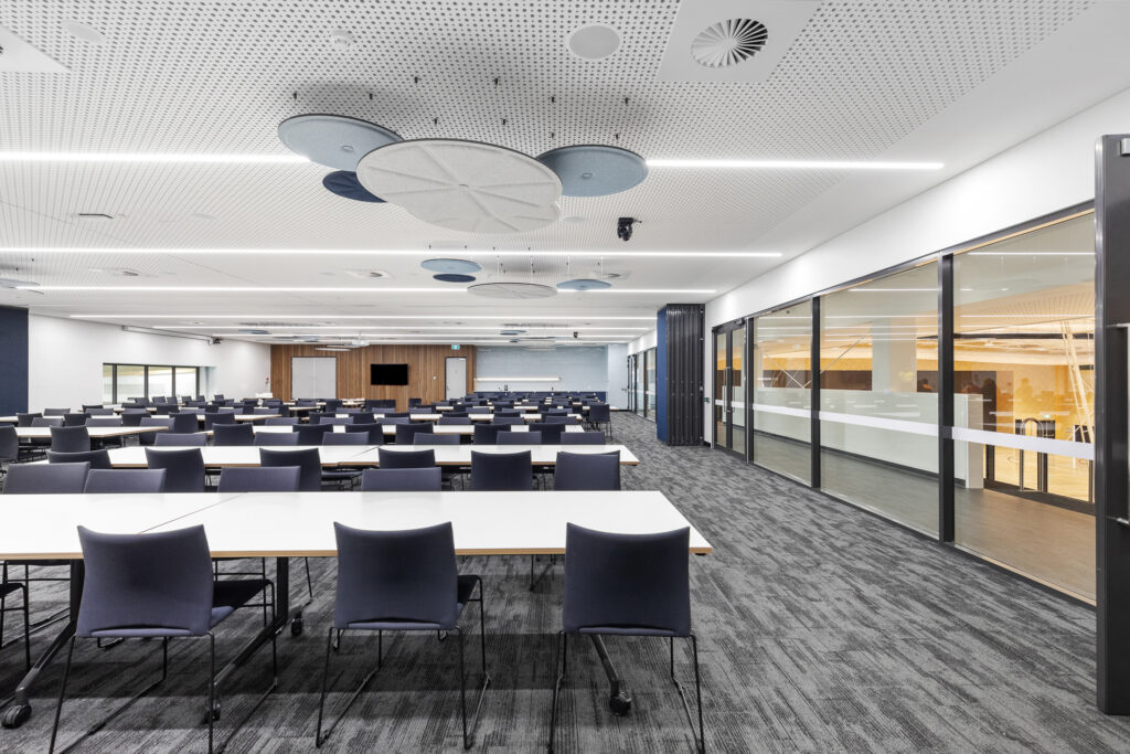 Large room with windows along the right hand side and tables set boardroom style